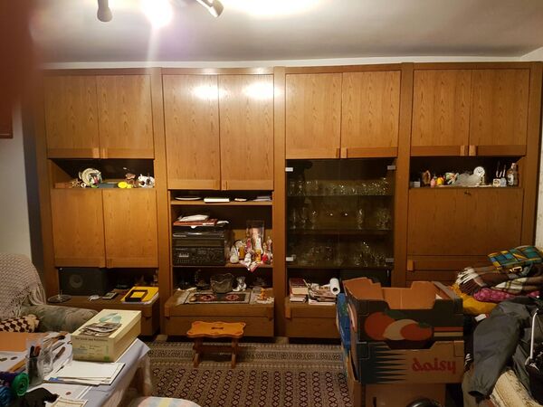 Große Wohnzimmer-Schrankwand aus Holz mit Glastüren, Dekoration und Umzugskartons davor.