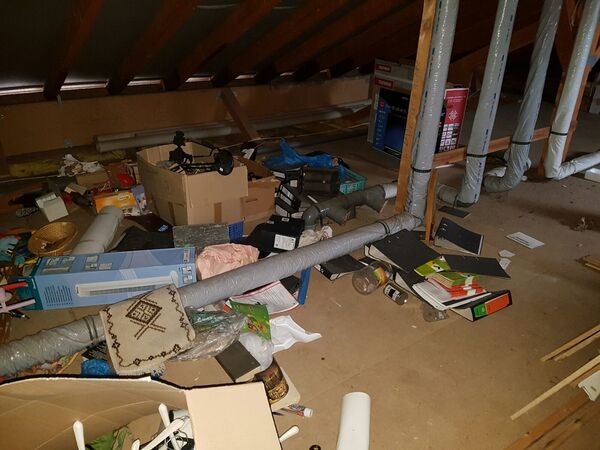 Unaufgeräumter Dachboden mit Kartons, Aktenordnern, Rohren und verschiedenen Gegenständen.