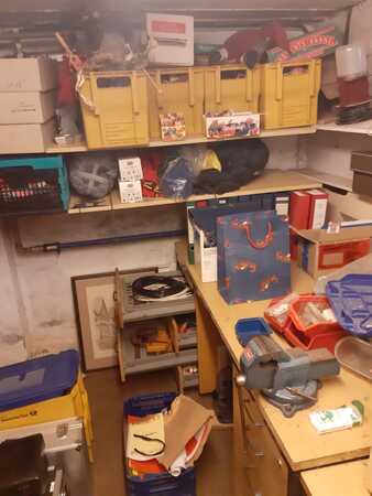 Kellerraum mit Regalen, Werkzeug, Kartons und gelben Kisten zur Aufbewahrung.